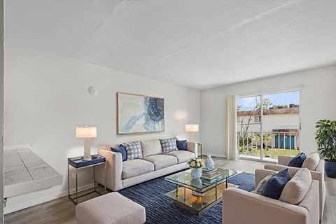 A living room with a couch, a table with a lamp, and a painting on the wall.